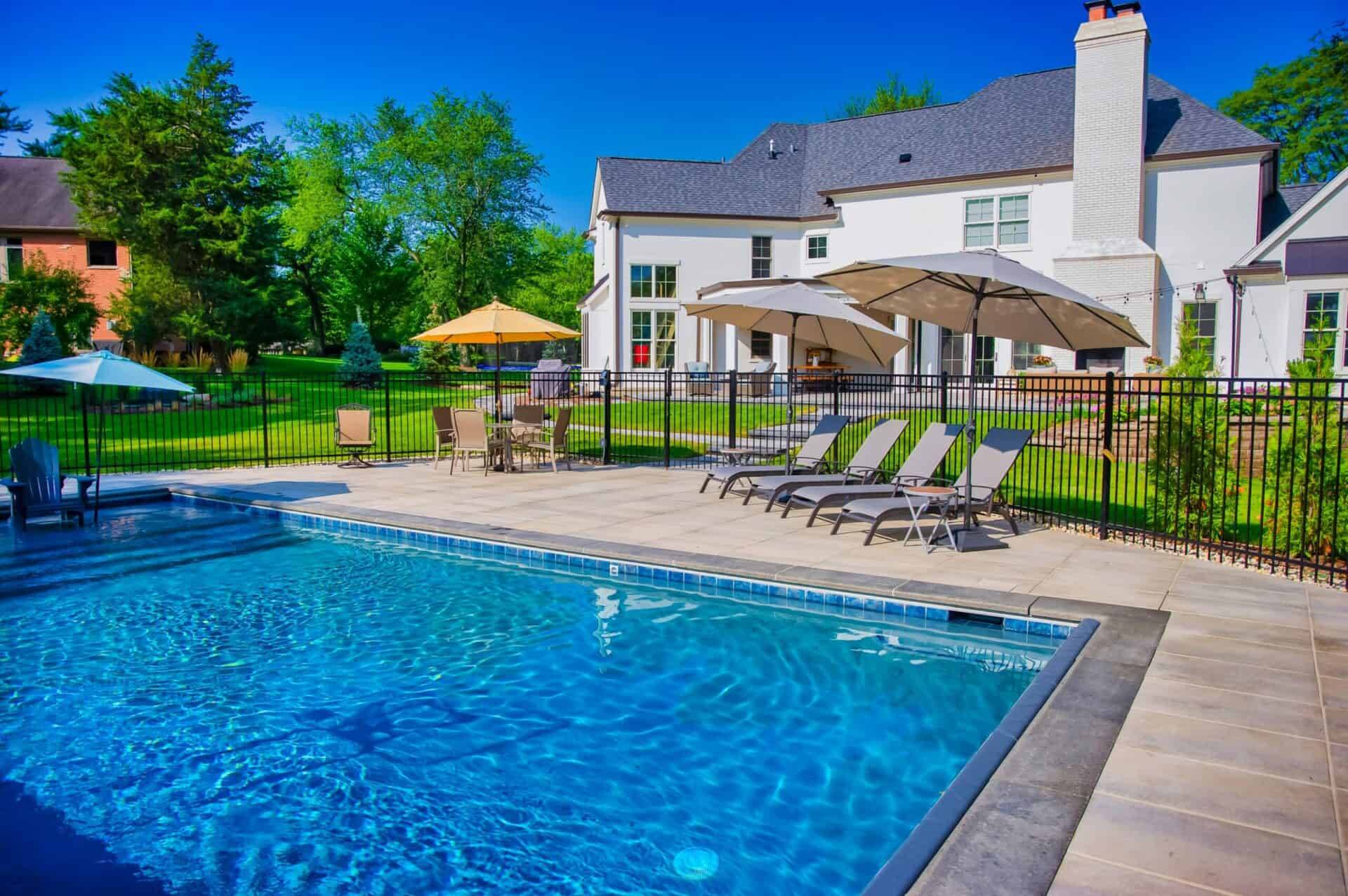 In-ground pool with a black aluminum safety fence and bluestone deck