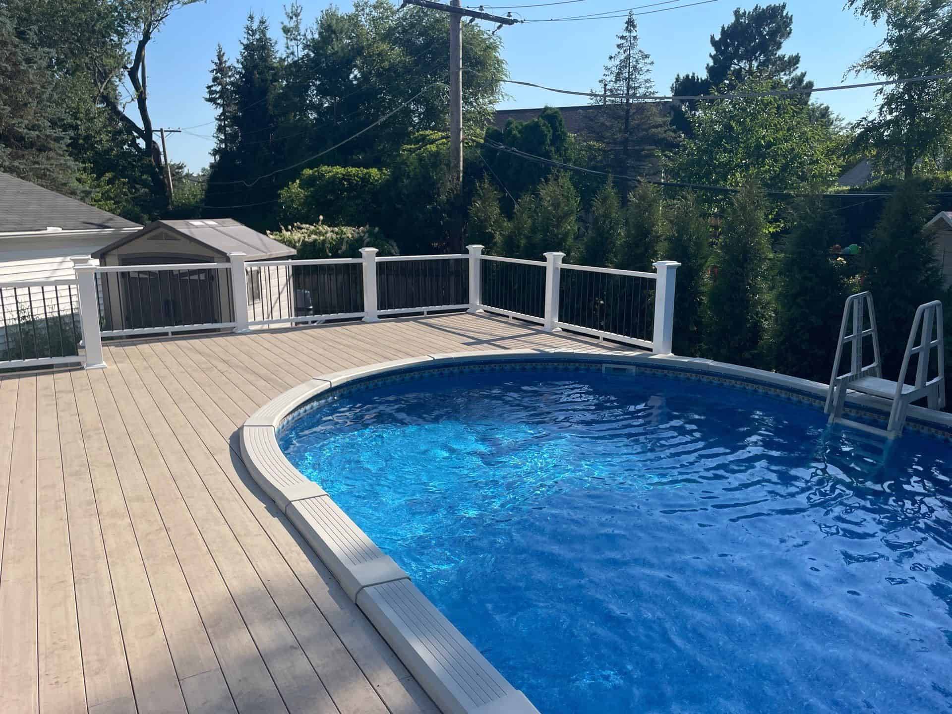 Above-ground pool with a composite wraparound deck and white railing